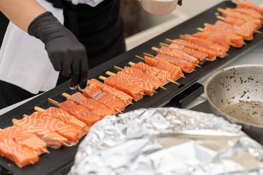 Salmon skewers being seasoned